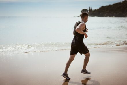 homme entrain de courir sur le sable en bord de mer