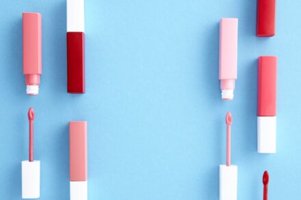 tubes de gloss et applicateurs posés sur une surface bleue