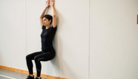 femme en train de faire la chaise, exercice de musculation en salle de sport